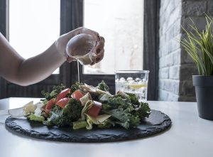 Person Pouring Dip on Vegetable Salad